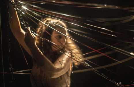 Photo 3 Une femme tire des bandes magnétiques pour les assembler sur scène tels des toiles d'araignée.