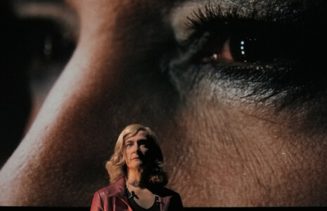 Photo 2 : Une femme sur scène, avec, derrière elle, un écran où est projeté un très gros plan sur les yeux d'une femme.