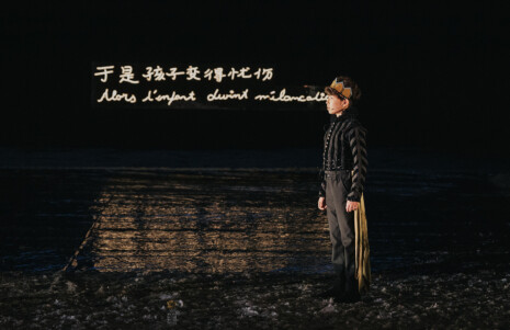 Photo 1 Le petit prince se tient debout, avec un écran noir sur lequel est écrit le texte en chinois et en français.