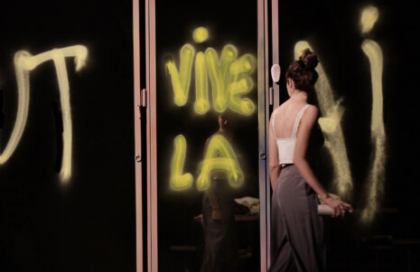 Photo 2 : Une femme écrit sur une surface avec une bombe de peinture. Elle écrit : "Vive la..."