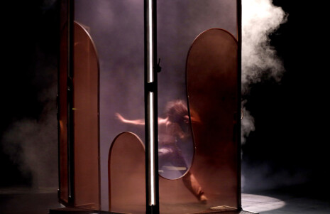 Photo 4 : Une femme danse derrière un paravent semi-transparent. Il y a de la fumée.